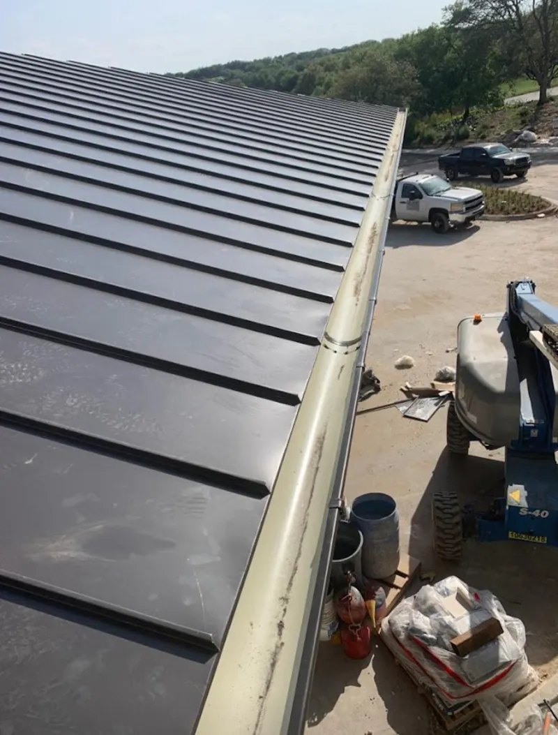 Standing seam panel and gutter detail on a metal roofing jobsite in Boylston